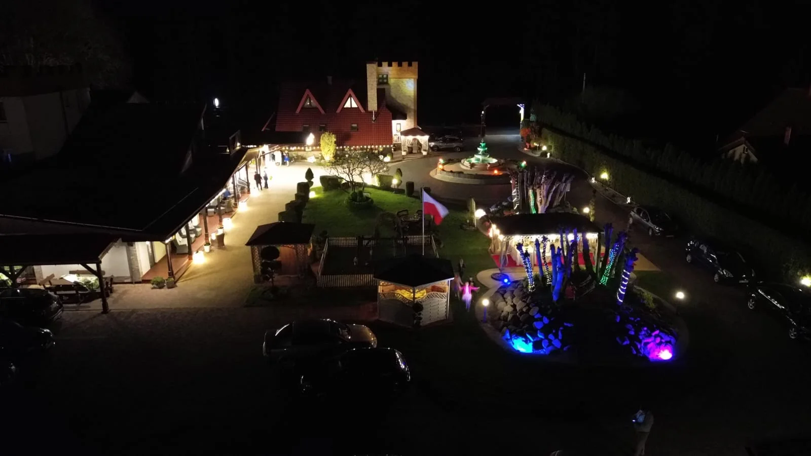 Teren Leśnej Nuty z oświetlonym ogrodem i zabudowaniami nocą